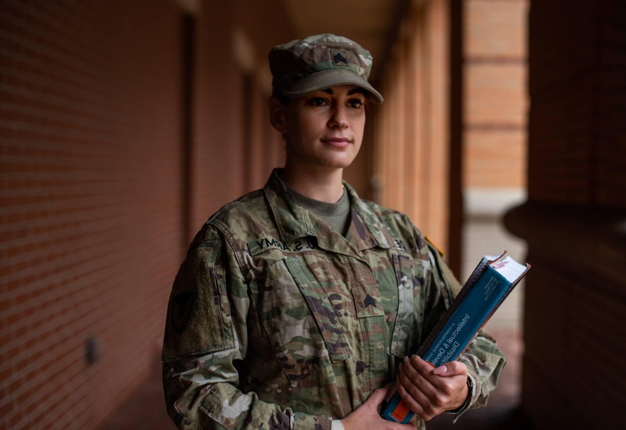 woman wearing army uniform holding books on campus